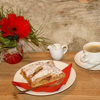 Apfelstrudel mit einer Tasse Kaffee und einem Kännchen Milch