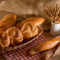 Weißgebäck in Körbchen und Ähren in kleiner Vase